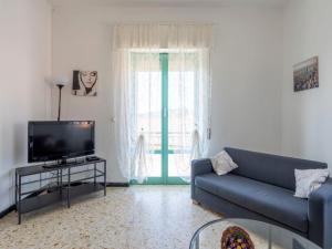 a living room with a blue couch and a tv at Apartment Carleadri by Interhome in Civezza