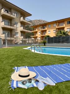 a hat and sunglasses on a blanket next to a swimming pool at RVHotels Apartamentos Tropic in L'Estartit