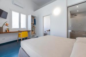 um quarto com uma cama branca e uma cadeira amarela em EGIDA camere mediterranee em Favignana
