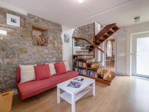 a living room with a red couch and a stone wall at Holiday Home Le Mura by Interhome in Cividale del Friuli