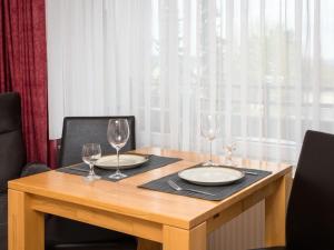 a wooden table with two plates and wine glasses on it at Apartment A110 by Interhome in Lahnstein
