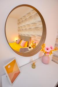 a mirror on a desk with a bed and flowers at SOFIA Cozy Apartment - Underground Private Parking in Bucharest
