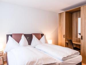 ein Schlafzimmer mit einem großen weißen Bett mit weißen Kissen in der Unterkunft Apartment TITLIS Resort 2-Zimmer Wohnung 5 by Interhome in Engelberg