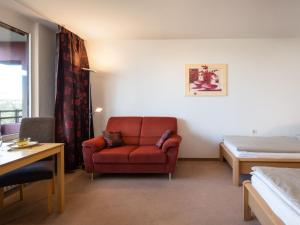 ein Wohnzimmer mit einem roten Stuhl und einem Bett in der Unterkunft Apartment B610 by Interhome in Lahnstein