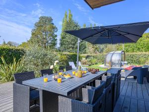 a wooden table with an umbrella on a deck at Holiday Home Blue Moustoir by Interhome in Carnac