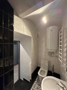 a white bathroom with a toilet and a sink at Котляревського апартамент з садом in Lviv