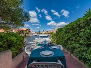 a table with a blue tablecloth and chairs next to a river at Holiday Home Nautica-3 by Interhome in Le Barcarès