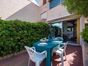 a table with a blue table cloth and white chairs at Holiday Home Nautica-3 by Interhome in Le Barcarès