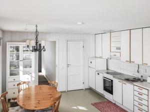 uma cozinha com armários brancos e uma mesa de madeira em Holiday Home Långahuset by Interhome em Västlax