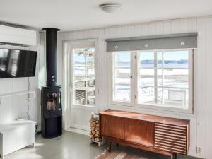 uma sala de estar com um fogão a lenha e janelas em Holiday Home Långahuset by Interhome em Västlax