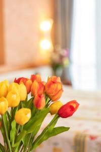 un bouquet de fleurs rouges et jaunes dans un vase dans l'établissement Cà Trifolera Barbaresco - Appartamento per 2 o 4 persone immerso nei vigneti - Free Parking Wi-Fi -, à Barbaresco