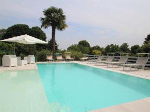 a large swimming pool with chairs and an umbrella at Villa Giuseppina by Interhome in Besozzo