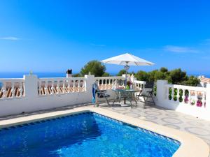 a villa with a swimming pool and a table and an umbrella at Villa Las Brisas by Interhome in Nerja