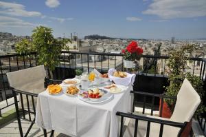 une table avec des assiettes de nourriture sur un balcon dans l'établissement Dryades & Orion Hotel, à Athènes