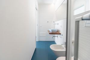 a white bathroom with a sink and a toilet at EGIDA camere mediterranee in Favignana