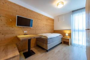 een slaapkamer met een bed en een bureau met een televisie bij Gass Apartment A in Laion