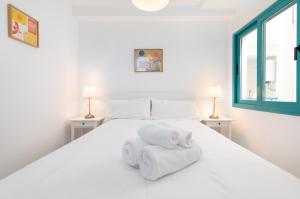 een slaapkamer met een wit bed en handdoeken bij Pont Sec Apartments in Denia