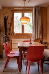 a dining room with a wooden table and red chairs at Terre de Sapins in Orbey