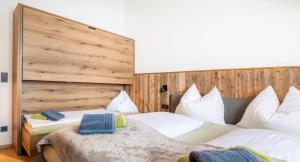 a bedroom with two beds and a wooden wall at Appartement Bergpanorama Brandegg in Wagrain