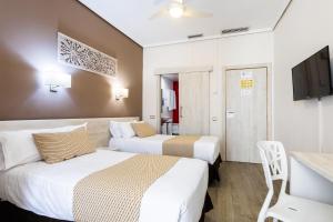 una camera d'albergo con due letti e una televisione di Sweet Hotel Continental a Valencia