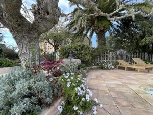 a garden with a bench and flowers and a tree at LA MAISON DE JUSTINE in Grimaud