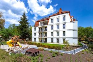 a white building with a playground in front of it at Bukowy Park Apartamenty in Polanica-Zdrój