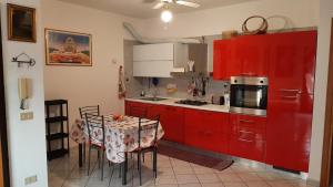 uma cozinha com armários vermelhos e uma mesa com cadeiras em PRESSI AEROPORTO COSTA SMERALDA em Olbia