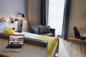 Schlafzimmer mit einem Bett und einem Laptop auf einem Schreibtisch in der Unterkunft acora Düsseldorf Airport Living the City in Düsseldorf