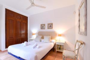 1 dormitorio con 1 cama con sábanas blancas y silla en Ereza Villa Paraiso, en La Oliva