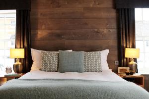 a bedroom with a bed with a wooden headboard and two lamps at The Red Lion in Odiham