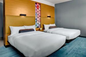 two beds in a hotel room with white sheets at Aloft Chapel Hill in Chapel Hill
