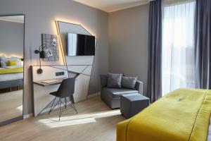 a bedroom with a bed and a desk and a chair at acora Düsseldorf Airport Living the City in Düsseldorf