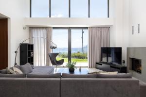 a living room with a large couch and a large window at SeaSilia Luxury Villa in Korakiaí
