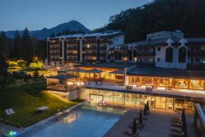 een groot gebouw met 's nachts een zwembad ervoor bij Grand Hotel Terme Di Comano in Comano Terme