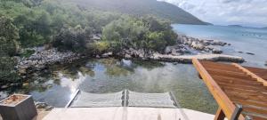Blick auf einen Strand mit zwei Stühlen im Wasser in der Unterkunft Private Villa by the sea in Žuljana