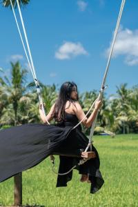 Una mujer está sentada en un columpio en Uma Linggah Resort, en Tampaksiring