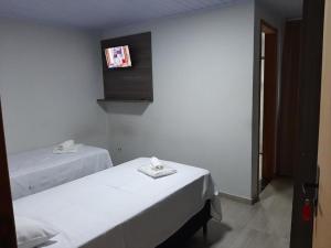 two beds in a room with a tv on the wall at Hotel ROF in Telêmaco Borba