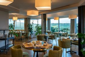 um restaurante com mesas e cadeiras e janelas grandes em Altarocca Wine Resort Adults Only em Orvieto