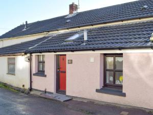 een huis met een rode deur en een zwart dak bij Sweet Pea Cottage in Llanelli