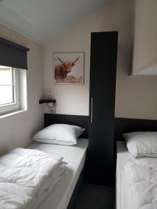 a bedroom with two beds and a cow picture on the wall at De Bijsselse Enk, Noors chalet 19 in Nunspeet