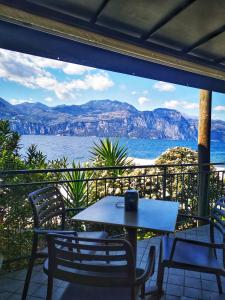 einen Tisch und Stühle auf einem Balkon mit Blick auf das Wasser in der Unterkunft Camping Baldo in Brenzone sul Garda