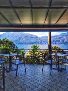 eine Terrasse mit Tischen und Stühlen und Blick auf das Wasser in der Unterkunft Camping Baldo in Brenzone sul Garda