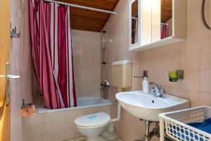 a bathroom with a sink toilet and a red shower curtain at House Domenico in Rovinj