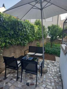 a table and chairs under an umbrella on a patio at Apartmani Ernesta in Selce