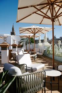 eine Terrasse mit Tischen und Sonnenschirmen auf dem Dach in der Unterkunft Nobu Hotel Sevilla in Sevilla