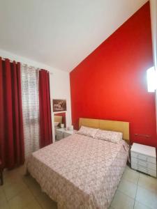 - une chambre dotée d'un lit avec un mur rouge dans l'établissement Villa Serene, à Plaia Grande