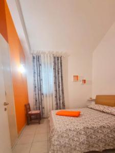 - une chambre avec 2 lits avec un oreiller orange dans l'établissement Villa Serene, à Plaia Grande