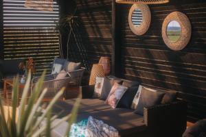 a living room with a couch with pillows and mirrors at Apartamenty Rodzinne Plater74 in Darłówko