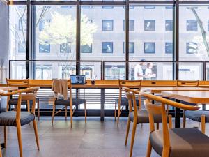 un restaurante con mesa, sillas y ventanas en Tokyu Stay Kanazawa, en Kanazawa