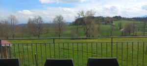 d'un balcon avec des chaises et une vue sur un champ. dans l'établissement La Grange de Léobin, à Colombier